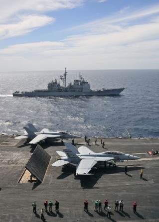 The Ticonderoga Class cruiser USS Leyte Gulf alongside the aircraft carrier USS Enterprise, while the latter conducts flight operations in the Red Sea. Enterprise stood by for potential action against the Gaddafi regime in Libya.  Photo: Jesse L. Gonzalez/US Navy. 
