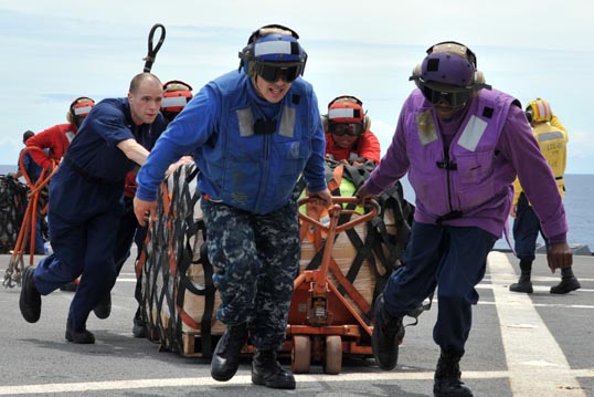 On their way from Singapore to Japan, sailors aboard the US 7th Fleet command ship USS Blue Ridge move pallets of humanitarian relief supplies across the ship's flight-deck during an underway replenishment with the USNS Rappahannock. Photo: Fidel C. Hart/US Navy.